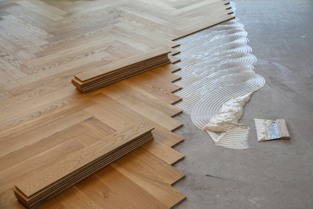 Worker laying parquet flooring and installing wooden laminate