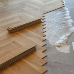 Worker laying parquet flooring and installing wooden laminate